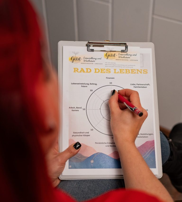 Rad des Lebens Eine Hand mit pinkem Stift schreibt auf ein Arbeitsblatt mit Diagramm und Text.